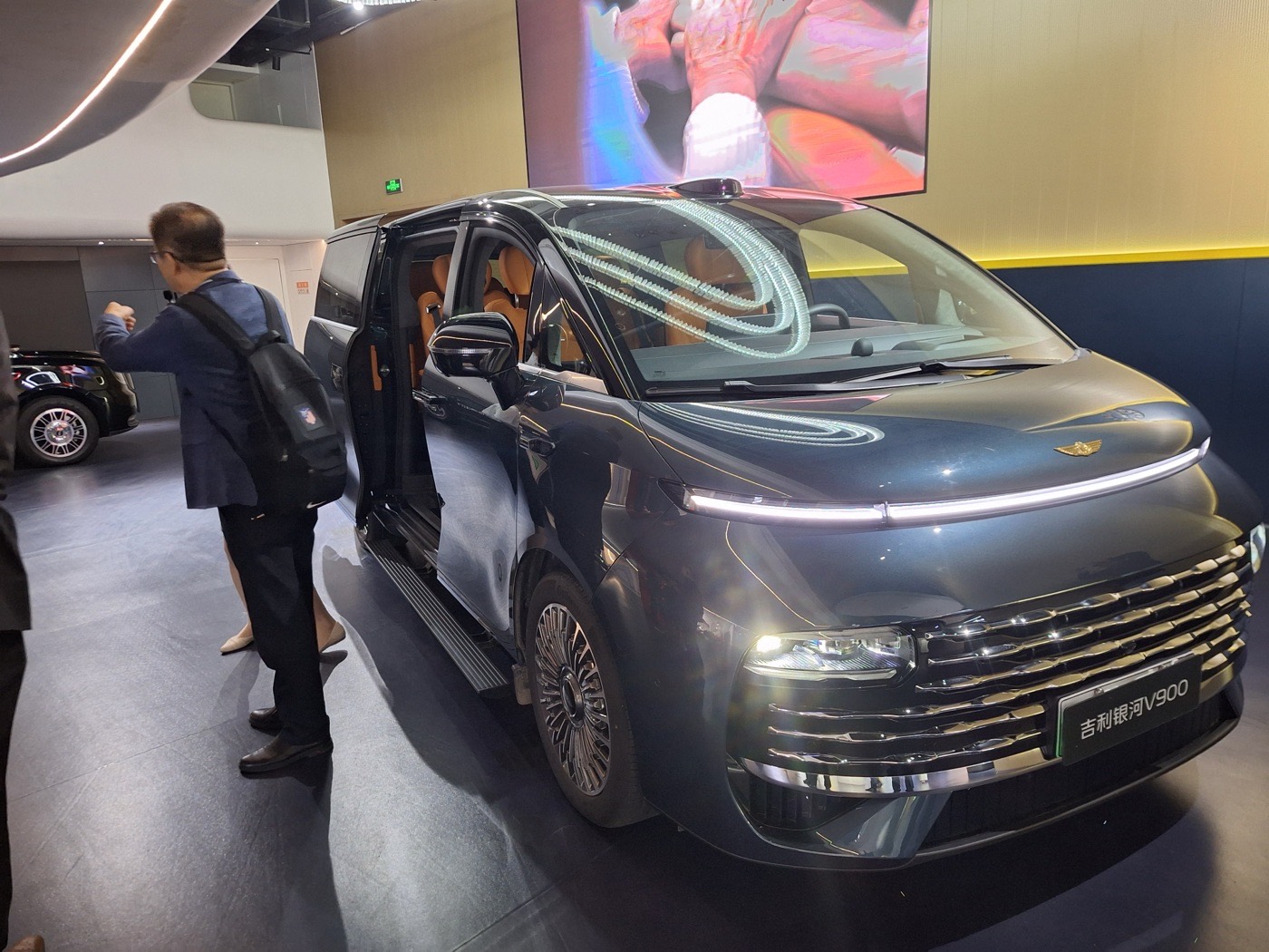 Un participant devant le monospace V900 dans le hall de Geely